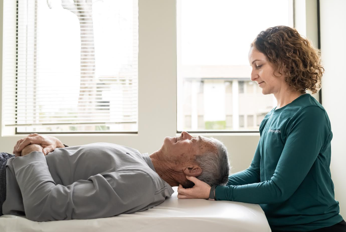 Physiotherapist examining a patient lying on a table in a clinical setting.